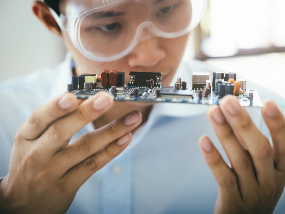 A man holding a circuit board, about to be deployed in an electronics product as a part of turnkey product assembly
