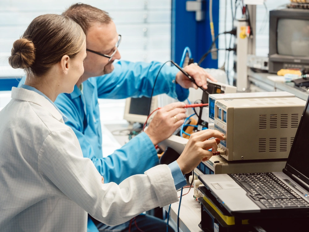 Two qualified workers testing an electronics product in a laboratory, a crucial step in the turnkey electronic manufacturing services