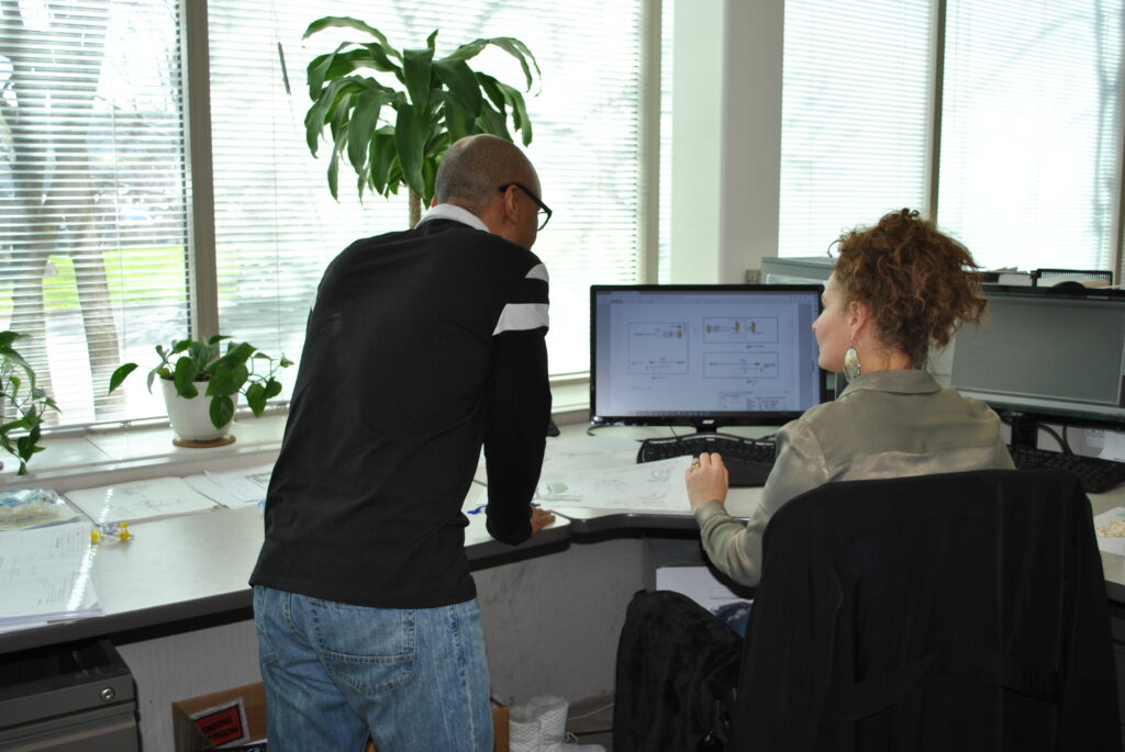 Engineers making design adjustments on a computer as part of a custom manufacturing services workflow to reduce production costs.