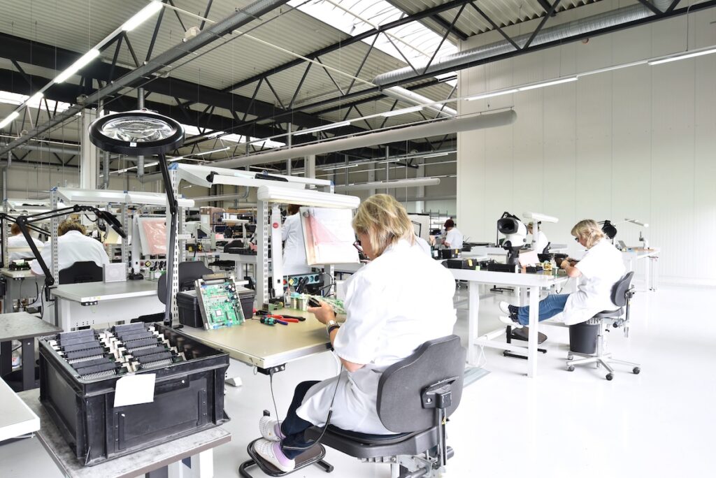 Technicians working in a structured assembly line, demonstrating the precision required for defense and aerospace product engineering services.