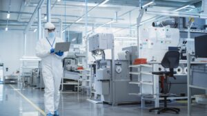 Person reviewing medical device engineering data on human factors while walking in a manufacturing facility and consulting with another engineer.